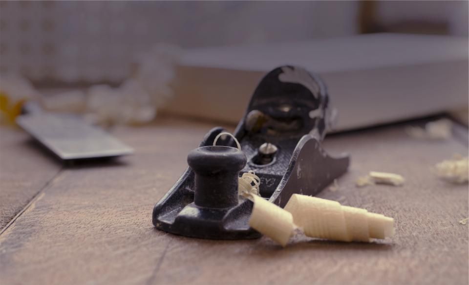 Antique hand plane with wood shavings on a bench